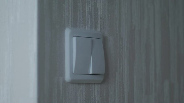 a child's hand turns the light on and off by pressing the keys of an electric switch, a child turns on the light in a room