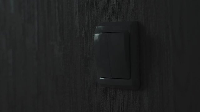 a child's hand turns the light on and off by pressing the keys of an electric switch, a child turns on the light in a room