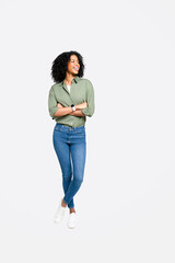 African-American woman stands in full length confidently against a white background, arms crossed,...