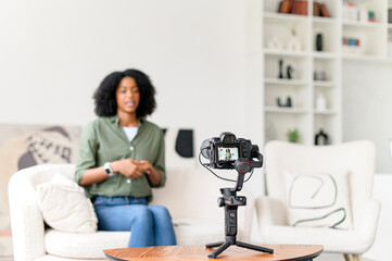 An African-American woman prepares to record an educational video, sitting comfortably in front of...
