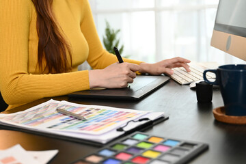 A woman is sitting at a desk with a yellow shirt on and is working on a color palette.