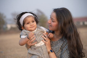 First Steps. Adorable smiling Indian mother walks with her infant son 
