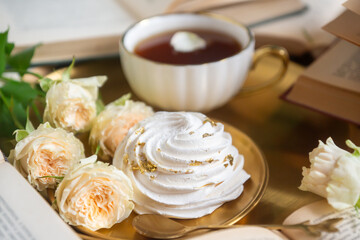 A cup of aromatic tea, a book and a rose on the table.