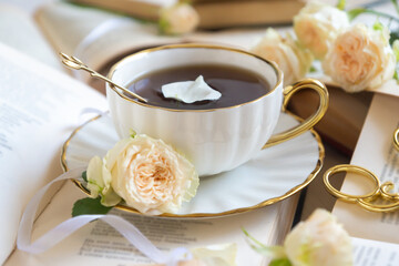 A cup of aromatic tea, a book and a rose on the table.