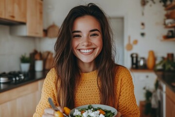 Young woman eating a healthy salad with feta cheese in the kitchen