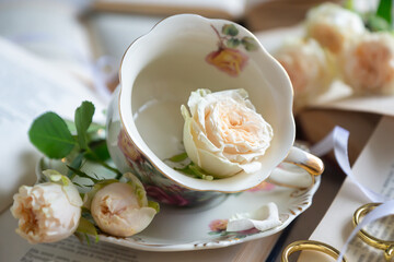 A cup of aromatic tea, a book and a rose on the table.