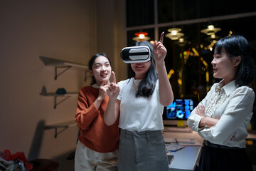 Asian businesswomen experiencing virtual reality headset in office at night, talking and interacting with virtual reality