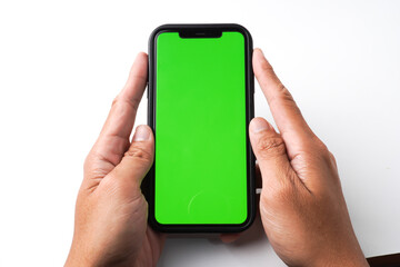 Someone hand is holding a smartphone with blank green screen display for mock up, isolated on white background. Social media scrolling, gaming and mobile apps concept