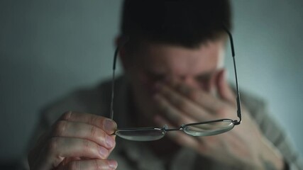 Pain in the eyes of a guy.
Eye strain.
Vision problems.
The man took off his glasses and rubbed his eyes from fatigue