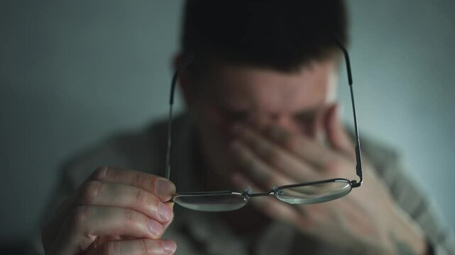 Pain in the eyes of a guy.
Eye strain.
Vision problems.
The man took off his glasses and rubbed his eyes from fatigue