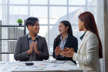 Diverse business team applauding together, sharing professional achievement in sleek corporate workspace