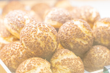 A beautifully designed restaurant communal space features sleek wooden benches positioned near a floor-to-ceiling glass facade, allowing natural light to flood the area. The warm tones of the wood