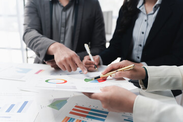 Business team analyzing financial charts and graphs pointing at statistics documents during a corporate meeting