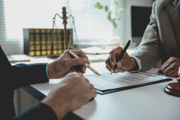 Professional lawyers reviewing contract details, gesturing with pens while analyzing legal...