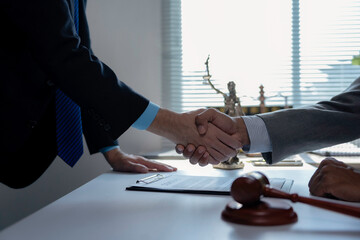 Professional lawyers finalizing agreement, shaking hands near gavel and Lady Justice statue in law...