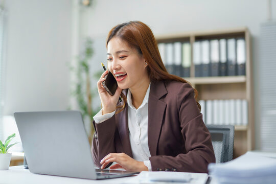 Professional businesswoman working simultaneously, handling phone conversation and digital tasks at contemporary workplace