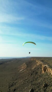 green paraglider flight over cliff vertical drone video kazakhstan 4K