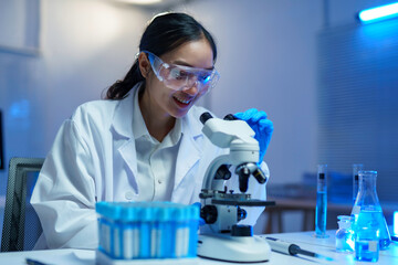 Female scientist examining microscope sample in medical research lab, focusing on healthcare...