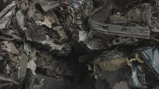 Pezzi di automobili demoliti e pressati da uno sfasciacarrozze