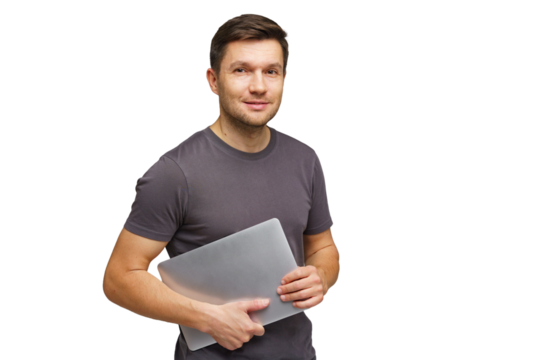 Man holding a laptop with a confident smile while standing indoors in casual attire - Powered by Adobe