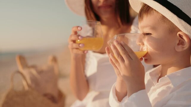 Mother and son enjoy a refreshing beverage together on a sunny beach. Capturing the essence of a perfect family vacation with a focus on relaxation and connection.
