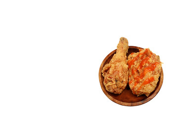 Fried chicken with sauce on top and served on a wooden plate, isolated on white background