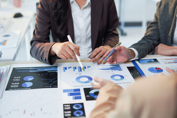 Business team analyzing financial data using charts and graphs, discussing strategies and making decisions in a collaborative office environment