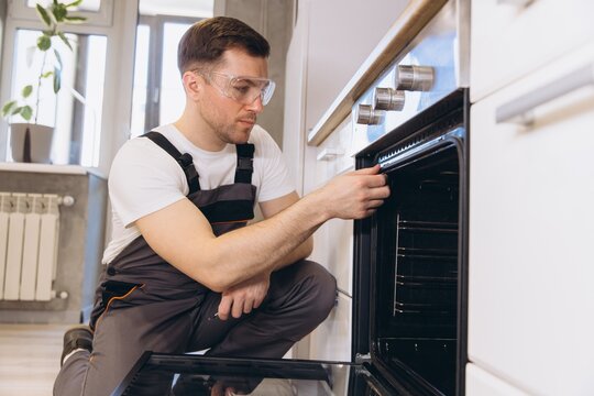 Professional plumber repairing oven in a modern kitchen