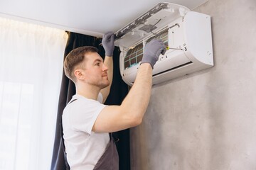 Plumber Repairing Air Conditioner Unit with Screwdriver