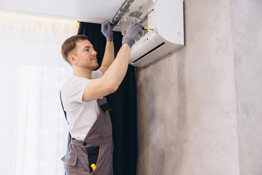 Professional plumber repairing air conditioner using screwdriver