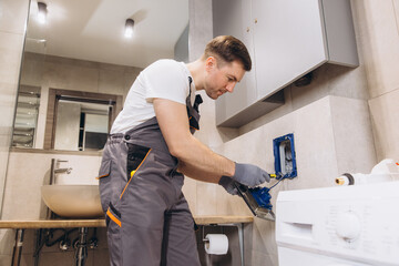 Plumber installing washing machine water supply in bathroom