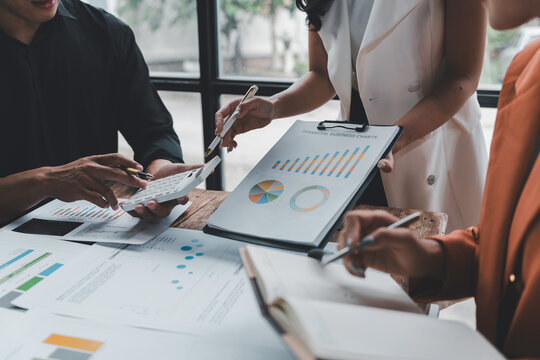 Business people working together analyzing financial charts and business graphs using calculator during a meeting in the office