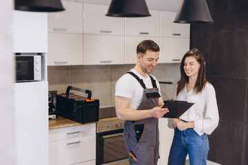 Plumber showing repair estimates to homeowner in kitchen