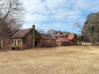 Obraz premium Abandoned Farmhouse and Barn Set Against a Cloudy Sky