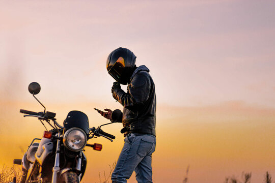 motorcyclist in leather jacket at sunset with helmet