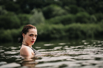 Fototapeta premium young woman swims in the pond and enjoys, rest in the lake river.