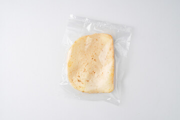 Indonesian traditional shrimp cracker (kerupuk udang) in transparent plastic packaging, isolated on white background.