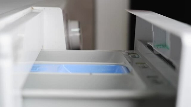 Woman pouring washing detergent and softener into the tray of a washing machine