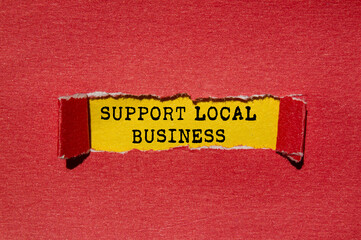 Support local business message written on ripped torn red paper on yellow background. Conceptual...
