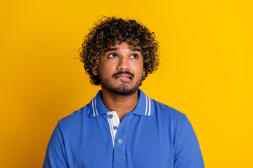 Portrait of a stylish young man standing against a vibrant yellow background, dressed in a fashionable blue polo shirt