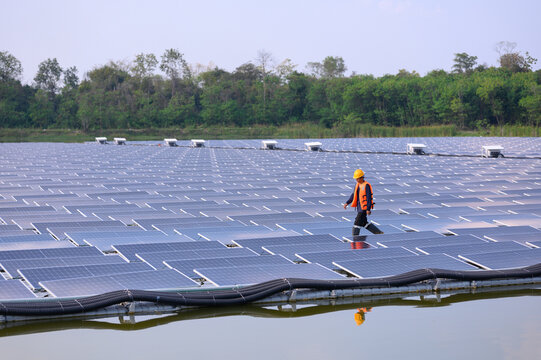 Professional workers clean and inspect solar panels on a floating buoy. Power plant with water
