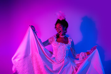 Joyful woman in royal gown dancing under neon lights at a masquerade ball, expressing elegance and happiness