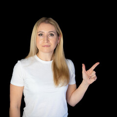Fototapeta premium positive young blonde woman pointing aside with fingers hand gesture at copy space advertising product, presenting sale discount promo offer standing isolated on black background.