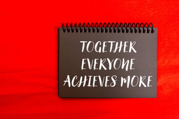 Obraz premium Together everyone achieves more message written on black notebook page on red background. Conceptual together everyone achieves more symbol. Copy space.