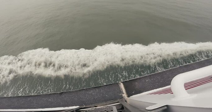 Top-view footage of the wavelets created by a moving ferry on a tranquil sea during daytime