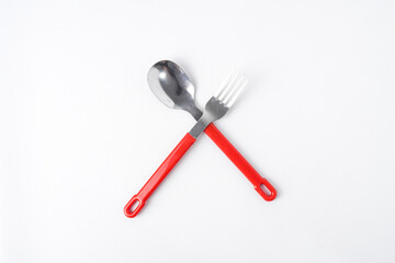 Empty white colored round shaped plate, red handle spoon and fork. Isolated on white background. Flat Lay Setup