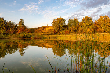 Fototapeta premium The calm surface of the water . Beautiful autumn colors along the river. The serenity and tranquility of an autumn morning on the banks of a narrow rural river.