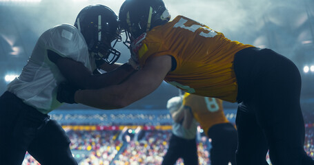 Professional Footballers Holding Off Competitors After Making a Ball Pass. Intense Action From an American Football Match During a Night Championship Game with Athletic Sportsmen