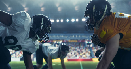 Professional Footballers Holding Off Competitors After Making a Ball Pass. Intense Action From an American Football Match During a Night Championship Game with Athleticism Sportsmen