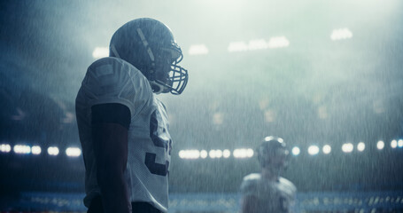 Portrait of Two Diverse American Football Teams Playing Ball with a Heavy Rain Forecast. Beautiful Shot of Strong Athletic Footballers in Professional Uniform Holding Each Other as the Game Starts